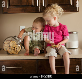 Jungen und Mädchen teilen Cookies auf Küchenarbeitsplatte Stockfoto