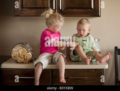 Jungen und Mädchen teilen Cookies auf Küchenarbeitsplatte Stockfoto