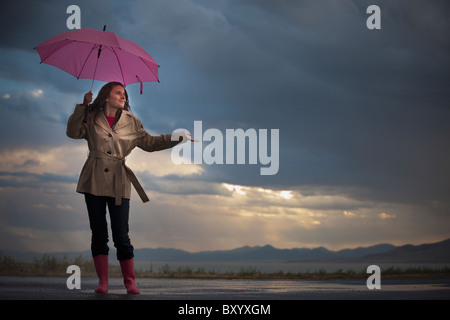 Junge Frau mit Regenschirm unter bewölktem Himmel Stockfoto