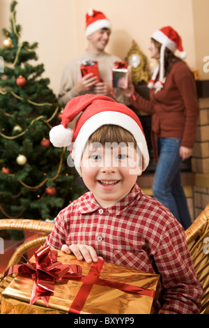 Glücklich Jüngling mit Geschenk in Händen, Blick in die Kamera Lächeln am Weihnachtstag Stockfoto