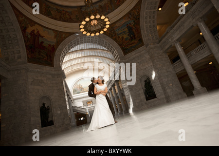 Braut und Bräutigam unter Bogen umarmen Stockfoto