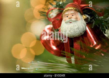 Nahaufnahme von dekorativen Spielzeug in Form von Santa und Glocken auf Tanne Zweig Stockfoto