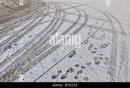 Reifenspuren und Fuß druckt links auf verschneiten und vereisten Straße Stockfoto