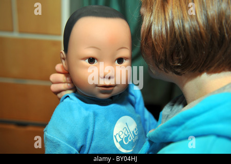 Ein 13 Jahres altes Mädchen kümmert sich eine "echte Pflege-Baby" für das Wochenende im Rahmen eines Schulprojektes, Teenager-Schwangerschaften zu verhindern Stockfoto