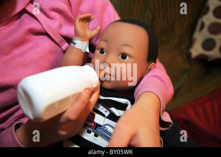 Ein 13 Jahres altes Mädchen kümmert sich eine "echte Pflege-Baby" für das Wochenende im Rahmen eines Schulprojektes, Teenager-Schwangerschaften zu verhindern Stockfoto