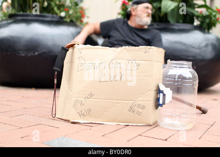 Ein Obdachloser sitzt und schreit nach Veränderung in schwierigen wirtschaftlichen Zeiten auf der Innenstadt-Mall in Charlottesville, Virginia. Stockfoto