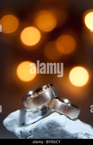 2 goldene Ringe auf einem weißen Felsen Stockfoto