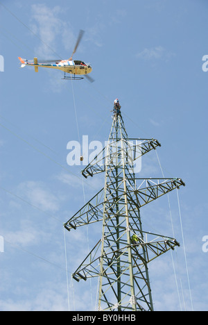 Hubschrauber macht Verbindungslinien, Arbeiter auf einem Strommast anbringen der Kabel, Österreich, Europa Stockfoto