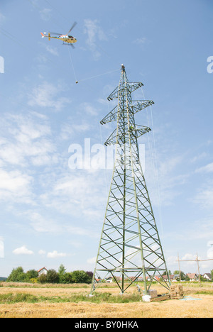 Hubschrauber macht Verbindungslinien, Arbeiter auf einem Strommast Befestigung für Kabel, Österreich, Europa Stockfoto