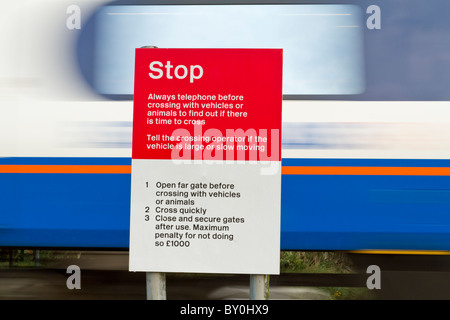 Warnhinweis. Schnelle Zug passiert ein Stoppschild in einem ungeschützten Bahnübergang auf einer Bahnstrecke in Nottinghamshire, England, Großbritannien Stockfoto