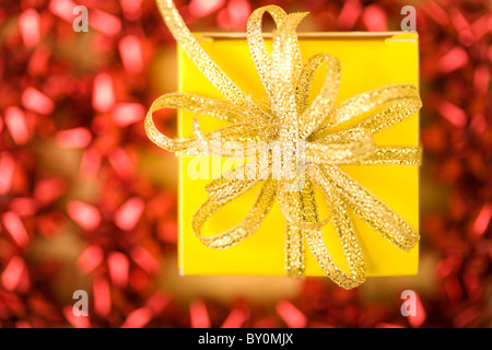 Ansicht von oben der goldenen Band auf Geschenkbox, umgeben von roten Dekorationen Stockfoto