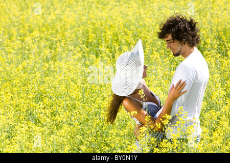 Foto des glücklichen Paares umarmen auf Wiese von gelben Blüten im Sommer Stockfoto