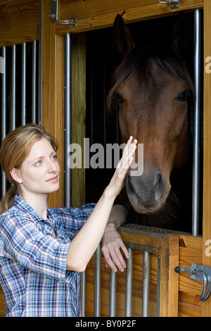 Mitte Erwachsene Frau mit Pferd im Stall Stockfoto