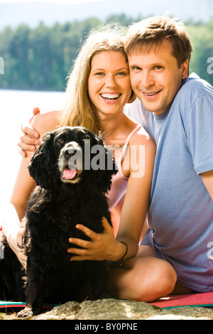 Porträt von glücklicher Ehemann umarmt seine schöne Frau mit schwarzen Hund in der Nähe von Stockfoto