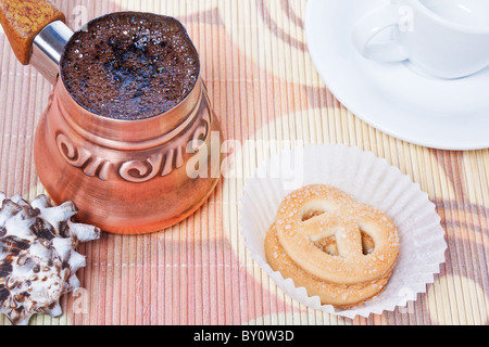 Frisch gebrühter Kaffee Türkisch in Kupfer Kaffeekanne mit Tasse, Keksen und Muschel als Dekoration Stockfoto