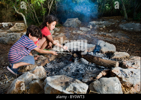 Kinder in ein Lagerfeuer in einem mediterranen Wald Stockfoto