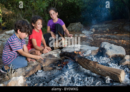 drei Kinder in ein Lagerfeuer in einem mediterranen Wald Stockfoto