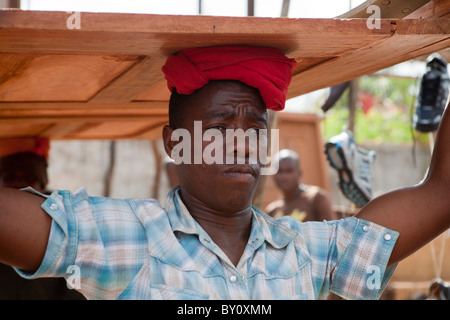 NAMPULA, Mosambik, Mai 2010: Sonntagsmarkt - führt ein Stall-Inhaber eine Holztür, die er gerade verkauft hat. Stockfoto