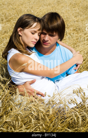 Bild von heiteren Mädchen auf Händen von ihrem Freund kuscheln, ihn mitten im Weizenfeld Stockfoto