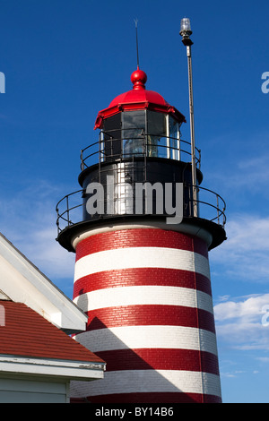 West Quoddy Head Lighthouse an einem Sommertag mit strahlend blauem Himmel und weißen Wolken. Stockfoto