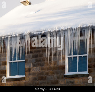 Lange Eiszapfen hängen von Dachrinnen in Goathland North Yorkshire Stockfoto
