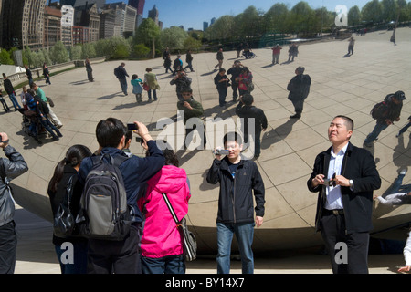 Besucher betrachten ihre Reflexion in der Cloud Gate Skulptur befindet sich an der AT&T Plaza im Millennium Park, Chicago, Illinois. Stockfoto