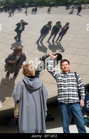 Besucher betrachten ihre Reflexion in der Cloud Gate Skulptur befindet sich an der AT&T Plaza im Millennium Park, Chicago, Illinois. Stockfoto