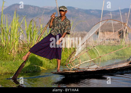 Myanmar, Inle-See.  Intha Fischer mit traditionellen konischen Fischnetz sanft seine Heimat mit flachem Boden Boot paddeln. Stockfoto