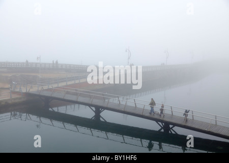 Fußgänger Fußgängerbrücke über Wasser mit Menschen an einem nebeligen Tag überqueren Stockfoto