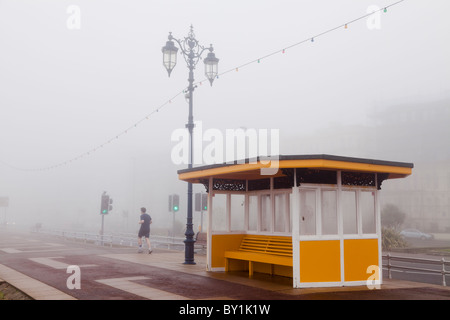 Joggen im Nebel an der Strandpromenade im Winter vorbei an einem Tierheim Stockfoto