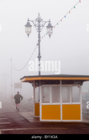 Joggen im Nebel an der Strandpromenade im Winter vorbei an einem Tierheim Stockfoto