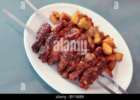 BBQ Chicken Wings am Spieß serviert mit Ofenkartoffeln Stockfoto