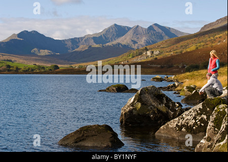 UK, Nord Wales, Snowdonia.  Mann und Frau stehen auf Felsen am Rand des Llyn Mymbyr mit dem Hintergrund des The Snowdon Stockfoto