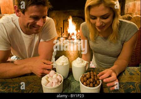 Gilar Farm, Snowdonia, Nordwales.  Ein paar genießen Sie heiße Schokolade, Marshmallows und Maltesers am offenen Feuer in der Sitzung Stockfoto