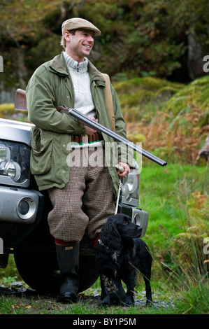 North Wales, Snowdonia; Gilar Farm. Ein Mann entspannt schiefen gegen seinen Landrover, während auf die Jagd. (MR) Stockfoto