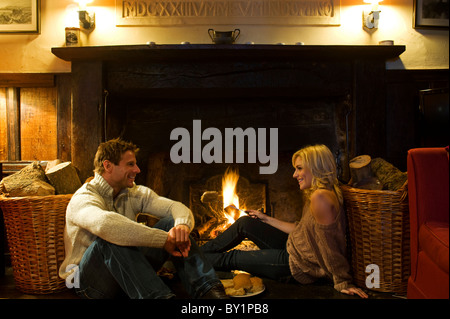 Gilar Farm, Snowdonia, Nordwales.  Ein paar entspannen während Toasten Fladenbrot auf dem offenen Feuer im Wohnzimmer dieses Stockfoto