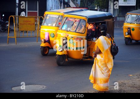 Eine Frau trägt einen gelben Sari warten darauf, überqueren Sie die Straße in Indien Stockfoto