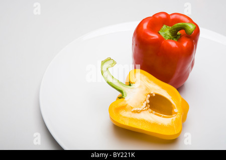 Nahaufnahme des roten Pfeffers mit Hälfte des gelben einen in der Nähe von auf weißem Hintergrund Stockfoto