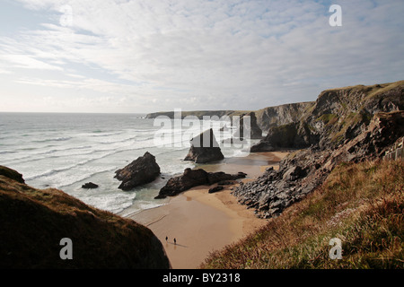 England, Cornwall, Bedruthan Steps. Ein paar gehen in Richtung der berühmten Felssäulen an diesem beliebten Strand der Nordküste. Stockfoto