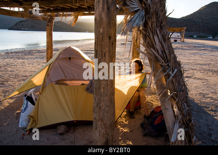 Eine reife Frau Lager unter einem Palapa am Playa Santispac, Baja California, Mexiko. Stockfoto