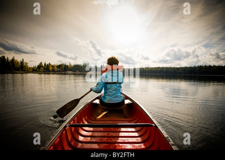 Eine junge Frau mit roten Haaren und eine blaue Jacke, Paddeln in einem Kanu. Stockfoto