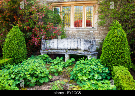 Eine Steinbank unter einer zweibogigen Fenster in einer abgelegenen Ecke des einen englischen Country-Sommergarten Stockfoto