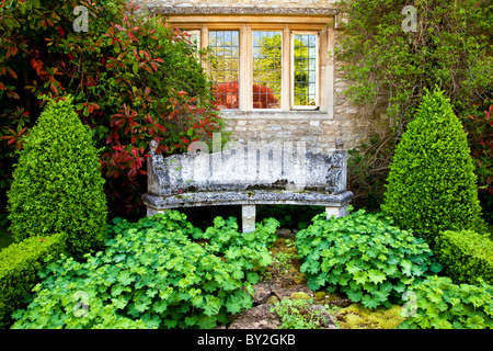 Eine Steinbank unter einer zweibogigen Fenster einer abgelegenen Ecke des einen englischen Country-Sommergarten Stockfoto