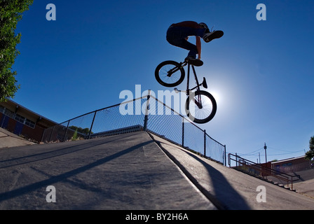 Ein Mountain-Bike-Fahrer hat einen Tailwhip auf eine konkrete Bank in Albuquerque, NM. Stockfoto