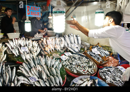 ISTANBUL, Türkei – Ein Verkäufer fängt ein Paket Fisch, das sein Kollege auf dem Karakoy Fischmarkt in der Nähe der Galata-Brücke in Istanbul geworfen hat. Diese traditionelle Marktpraxis demonstriert die fachkundige Koordinierung zwischen Arbeitnehmern, die frische Meeresfrüchte aus dem Bosporus und den nahe gelegenen Gewässern handhaben. Stockfoto