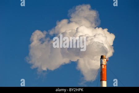 Rauch, Gas und Dampf Wogen aus einem Schornstein vor blauem Himmel. Stockfoto