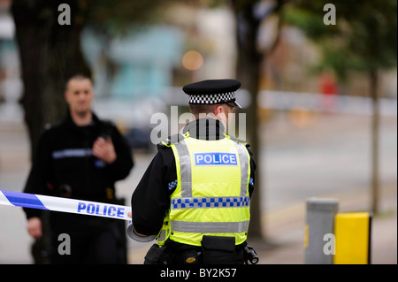 Ein Polizist Absperrungen aus der Szene eines Vorfalls oder Kriminalität Polizei Klebeband Stockfoto