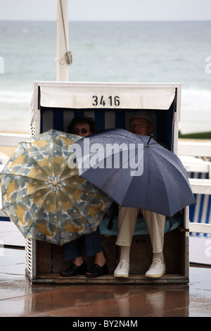 Leute sitzen im Strandkorb mit Sonnenschirmen, Westerland, Deutschland Stockfoto