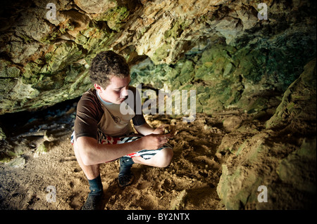 Ein junger Mann schaut Hornstein Einlagen in einer Höhle auf der Insel Santa Cruz aus Santa Barbara, CA. Stockfoto