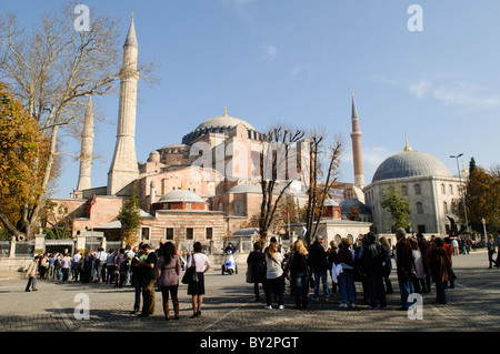 Hagia Sophia Kuppeln und Minarette Istanbul Türkei // ISTANBUL, Türkei — die Hagia Sophia vom Sultan Ahmet Park aus gesehen, zeigt ihre charakteristischen Kuppeln, Minarette und Stützen vor der Skyline von Istanbul. Das Äußere des Gebäudes spiegelt sowohl seine byzantinischen Ursprünge als auch die osmanischen Anbauten wider, wobei die zentrale Kuppel von vier Minaretten flankiert wurde, die nach der Umwandlung in eine Moschee im Jahr 1453 hinzugefügt wurden. Stockfoto